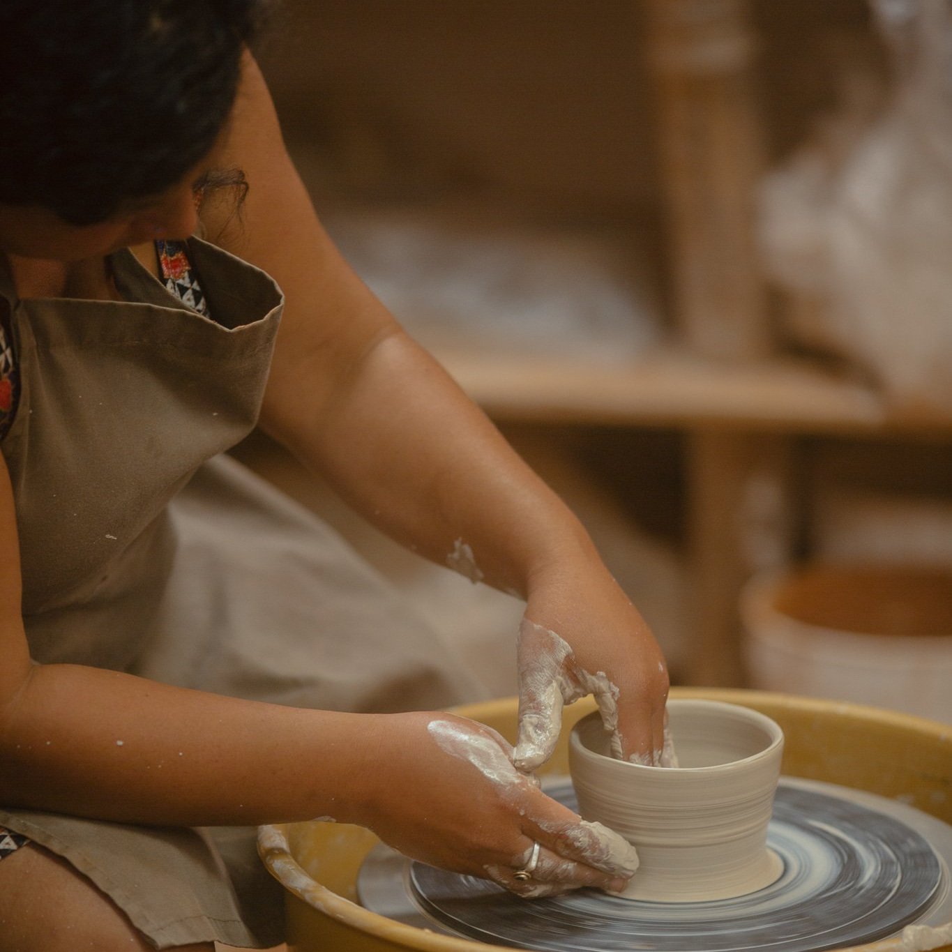 Hands shaping clay on the pottery wheel