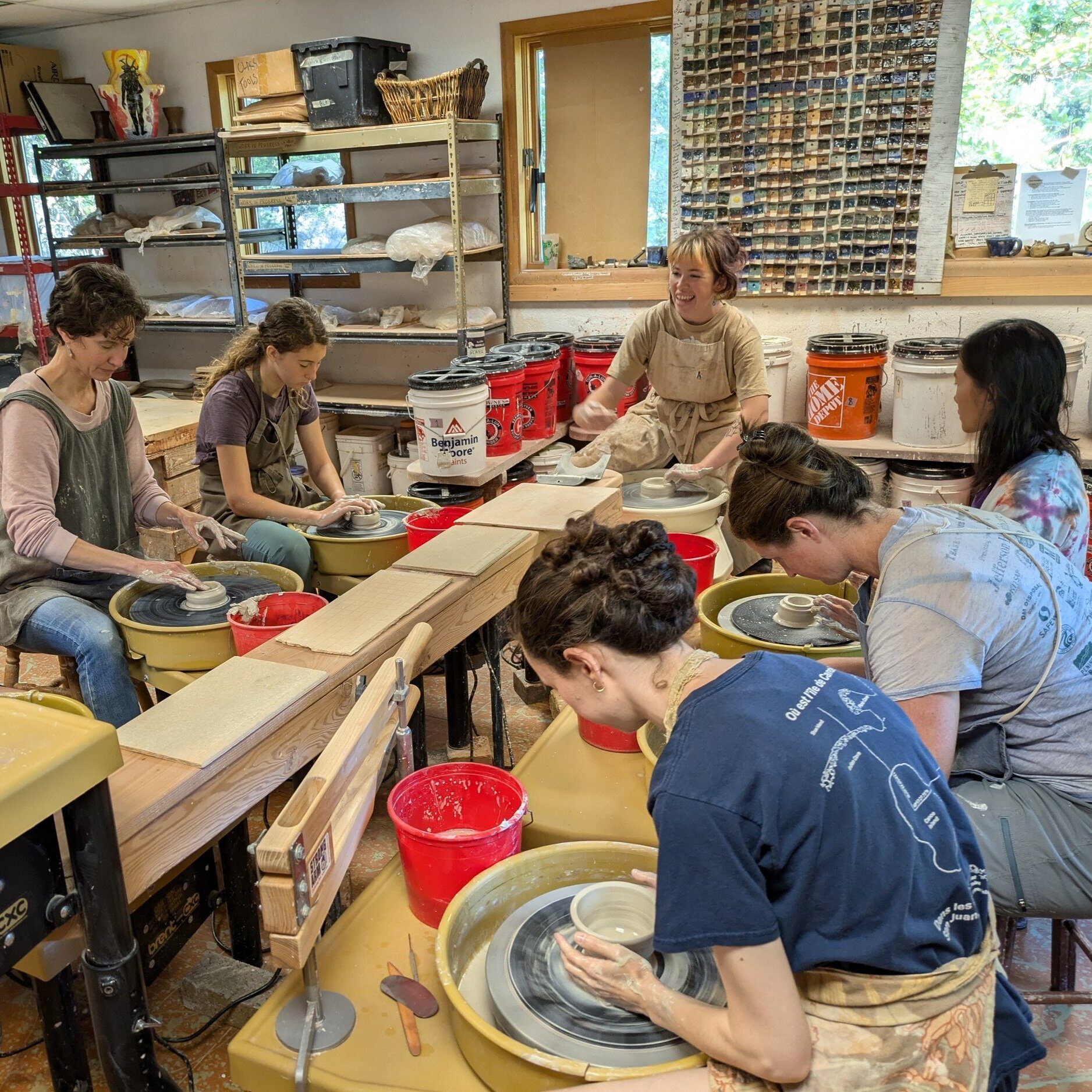 A group throwing pots at a row of wheels