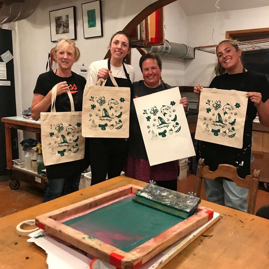 A group holding up their screenprinted tote bags